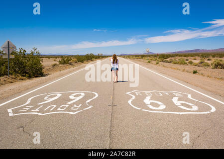 Young woman standing on the Route 66 road in Californian desert. United States Stock Photo