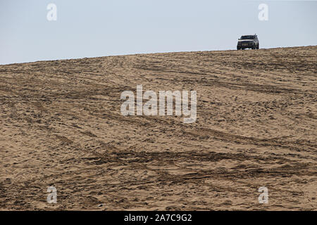 A lone four wheel drive perched at the top of a dune at Sealine Shore south of Doha, Qatar. Stock Photo