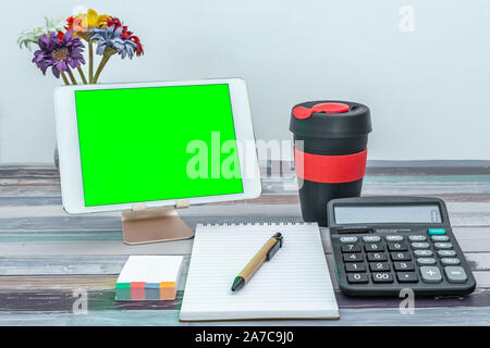 Office and school stationery supplies, reusable cup, mobile tablet with green screen. Business Objects Technology concept. Stock Photo