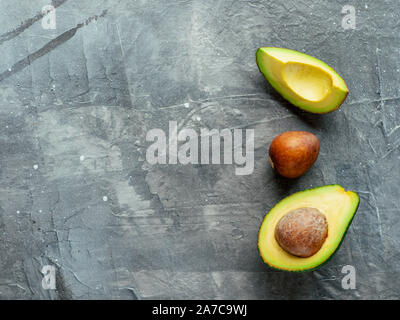 Avocado with copy space. Top view of avocado half, quarter and avocado pit on gray background. Food background Stock Photo