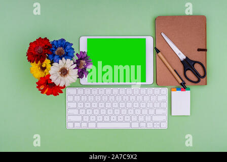 Green screen tablet, keyboard, office school stationery on green background. Flat lay top down view. Business Objects Technology concept. Stock Photo