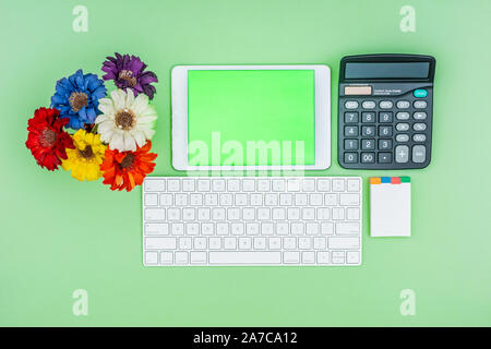 Green screen tablet, keyboard, office school stationery on green background. Flat lay top down view. Business Objects Technology concept. Stock Photo
