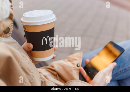 Minsk, Belarus, October 27, 2019: Woman drinks hot tea from paper biodegradable cup Stock Photo