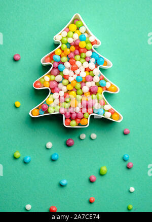 Creative layout of Christmas tree made of colorful candies over green background. Stock Photo