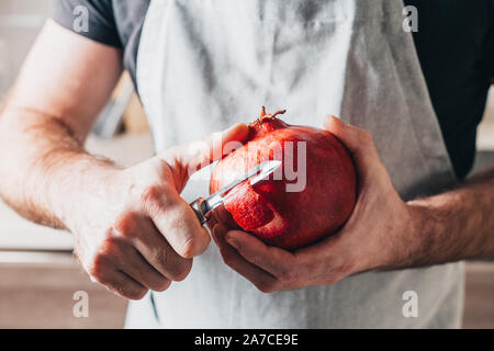 A man cleans ripe juicy large pomegranate - peeling Stock Photo