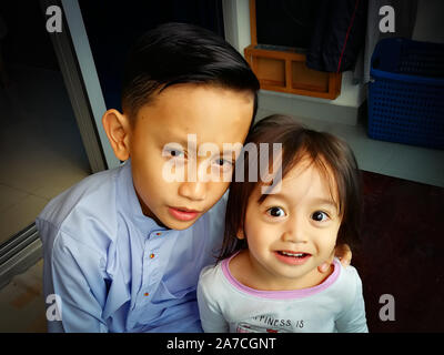 Portrait of asian brother and toddler sister. Family love bonding together concept. Brother is wearing traditional Malay suit. Stock Photo