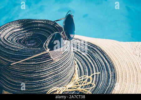 Fashionable women's accessories - glasses and a hat - near the pool Stock Photo