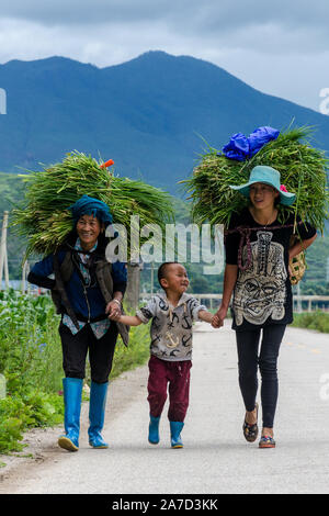 A family of farmers walks back home after a day of work, Lige, Lugu Lake, Yunnan, China Stock Photo