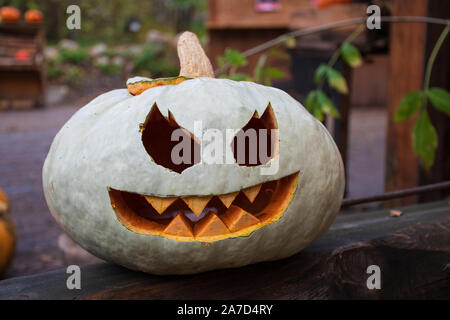 Spooky white and orange Halloween pumpkin, Jack O Lantern on a wooden table Stock Photo