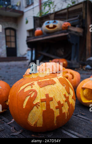 Spooky Halloween pumpkins with drawings of ghost, crosses and devil on a wooden floor, vertical Stock Photo