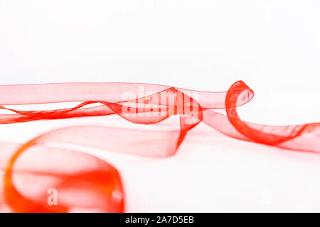 Elegant plays of color and transparency with a red organza ribbon that winds over a white background copy space Stock Photo