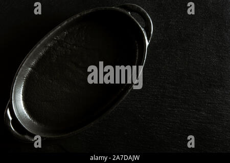 Black oval form for baking stands on a black background of stone Stock Photo