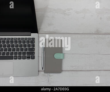 Top View of Laptop with Organizer Diary and Silver Pen on a Clean White Wooden Table Stock Photo