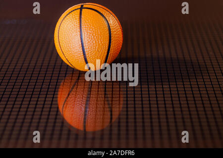 orange basket ball and his reflected image on a dark checkered background Stock Photo