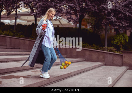 Happy modern young woman descending the stairs Stock Photo