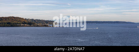 Beautiful View of Discovery Park and Mt Rainier in background on the Ocean Shore during a cloudy autumn evening. Taken in Smith Cove Park, Seattle, Wa Stock Photo