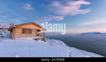 A wooden house, Barents sea at sunset in Teriberka, Murmansk Region, Kola Peninsula. Russia. Stock Photo