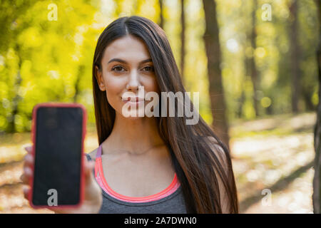 Confident woman showing the screen of her phone Stock Photo