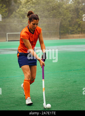 Female hockey player exercising on a grass field. Stock Photo
