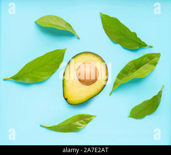 Avocado with leaves on blue background. Top view Stock Photo