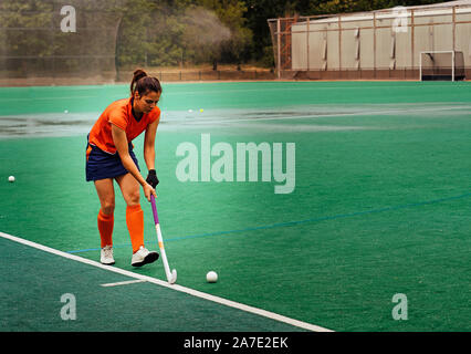 Female hockey player exercising on a grass field. Stock Photo