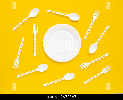 Plastic dish, spoon and fork on yellow background. Stock Photo