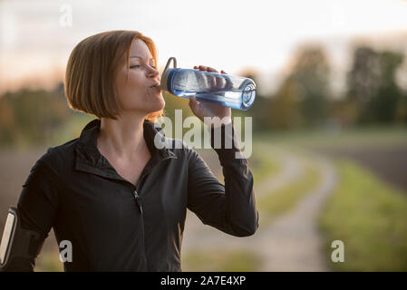 Close up of young woman drinking water during sports Stock Photo