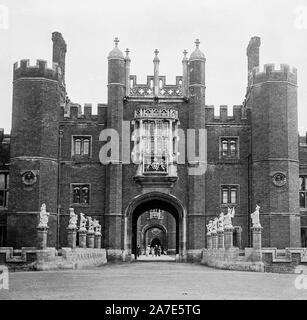 A vintage late Victorian or early Edwardian black and white photograph showing the entrance to Hampton Court Palace in England.. People visible in the entrance. Stock Photo