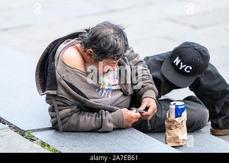 New Orleans, USA - April 23, 2018: People homeless man lying down on steps of street in Louisiana city with beer bottle Stock Photo