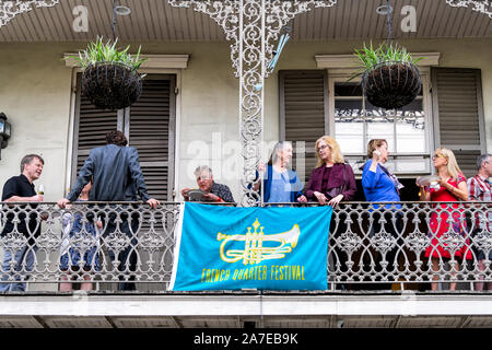 New Orleans, USA - April 23, 2018: Old town street in Louisiana city with people on balcony by French Quarter Festival banner sign Stock Photo