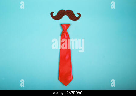 Mustache and tie on blue background. Isolated image. Concept Stock Photo