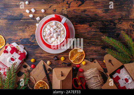 hot chocolate cacao with marshmallows knitted hand made red cloth for a mug top view packaging gifts and presents christmas decoration Stock Photo
