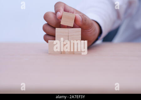hand holding and arranging wood block stacking as step stair with space for your content in wooden block Stock Photo