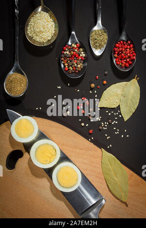 Spices in metal spoons and eggs on a cutting board Stock Photo
