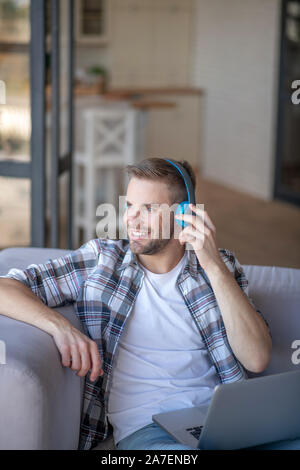 Bearded young man wearing blue headphones smiling Stock Photo