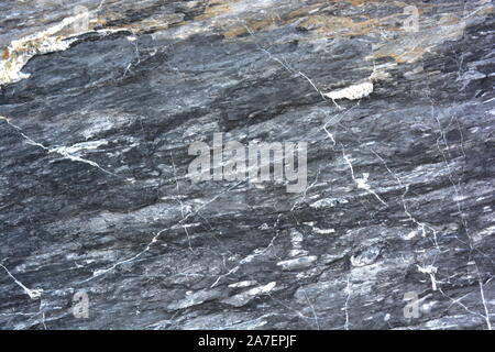 Natural granite rocks with veins of marble and minerals in intricate patterns for backgrounds, with surfaces eroded by the weather and the ocean Stock Photo
