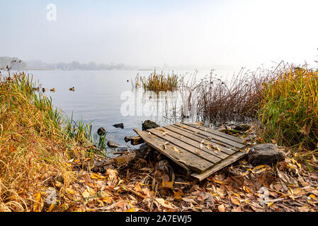 A wooden pontoon over big stones close to the blue Dnieper river is waiting for the fisherman. Stock Photo