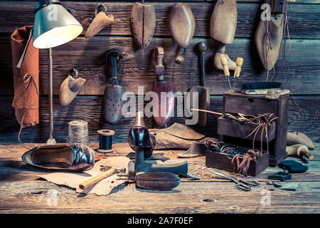 Workshop with shoes, tools and leather on wooden table Stock Photo