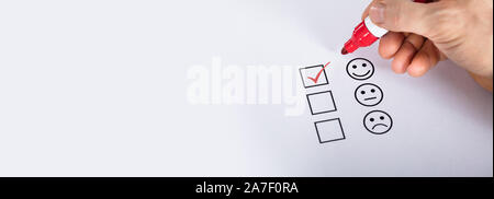 Satisfied Customer Putting Check Mark On Quality Service Survey Checklist Next To Drawn Happy Face Stock Photo