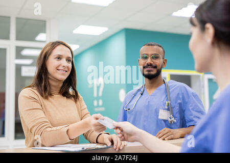 Patient giving credit card to receptionist in clinics to pay for medical service Stock Photo