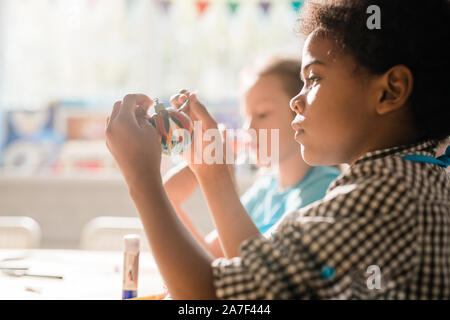 Cute African schoolboy holding handmade decorative Christmas toy ball Stock Photo