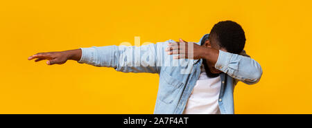 Man throwing dab, making internet meme pose on yellow background Stock Photo