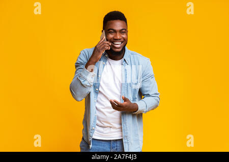 Cheerful black guy talking on phone and laughing out loud Stock Photo