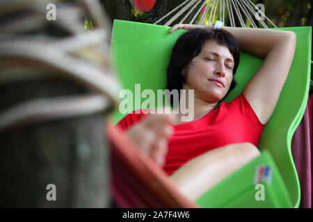 The girl is sleeping in a hammock. The girl is resting in a hammock in the country. Stock Photo