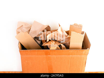 Cardboard box with crumpled paper and cardboard pieces against white wall. Close-up. Stock Photo