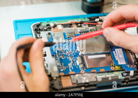 Two small soldering-irons in hands of professional repairman during work Stock Photo