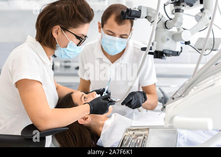 Highly qualified dentists making treatment in modern dental clinic Stock Photo