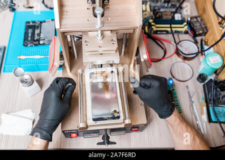 Gloved hands of professional repairman using equipment for gadget repair Stock Photo
