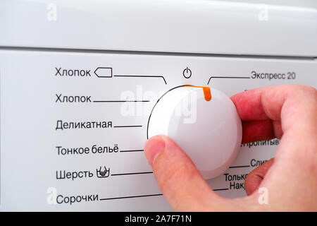 Close-up of person hand choosing cycle program on washing machine. Stock Photo