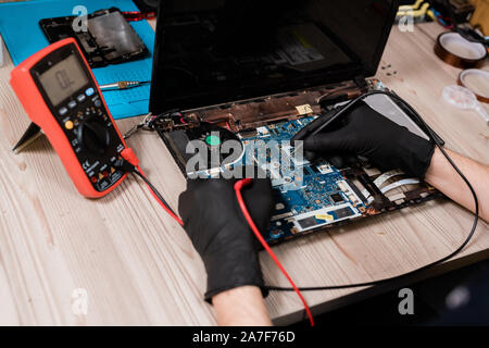 Master of repair service using soldering-irons while working over broken laptop Stock Photo